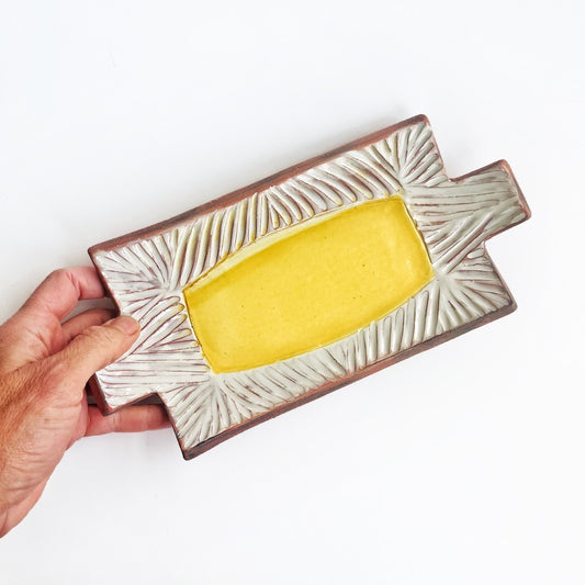 This slab built rectangle dish is great for serving snacks, appetizers, sushi plate, or fun lunch plate! Made from lowfire red earthenware clay, the hand carved white pattern and yellow glaze makes a beautiful statement contrasting with the red clay.