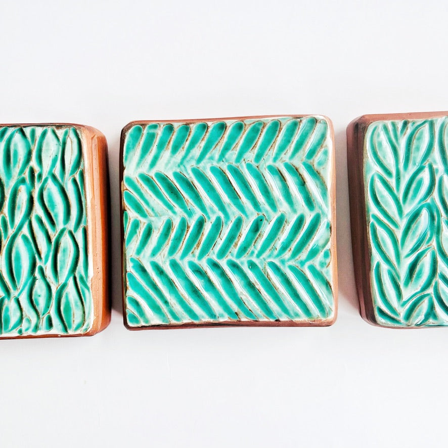 This square wall tile is made from red earthenware clay. The hand carved green leaf pattern contrasts nicely with the red clay. Simply display on your wall alone, or in a grouping.
