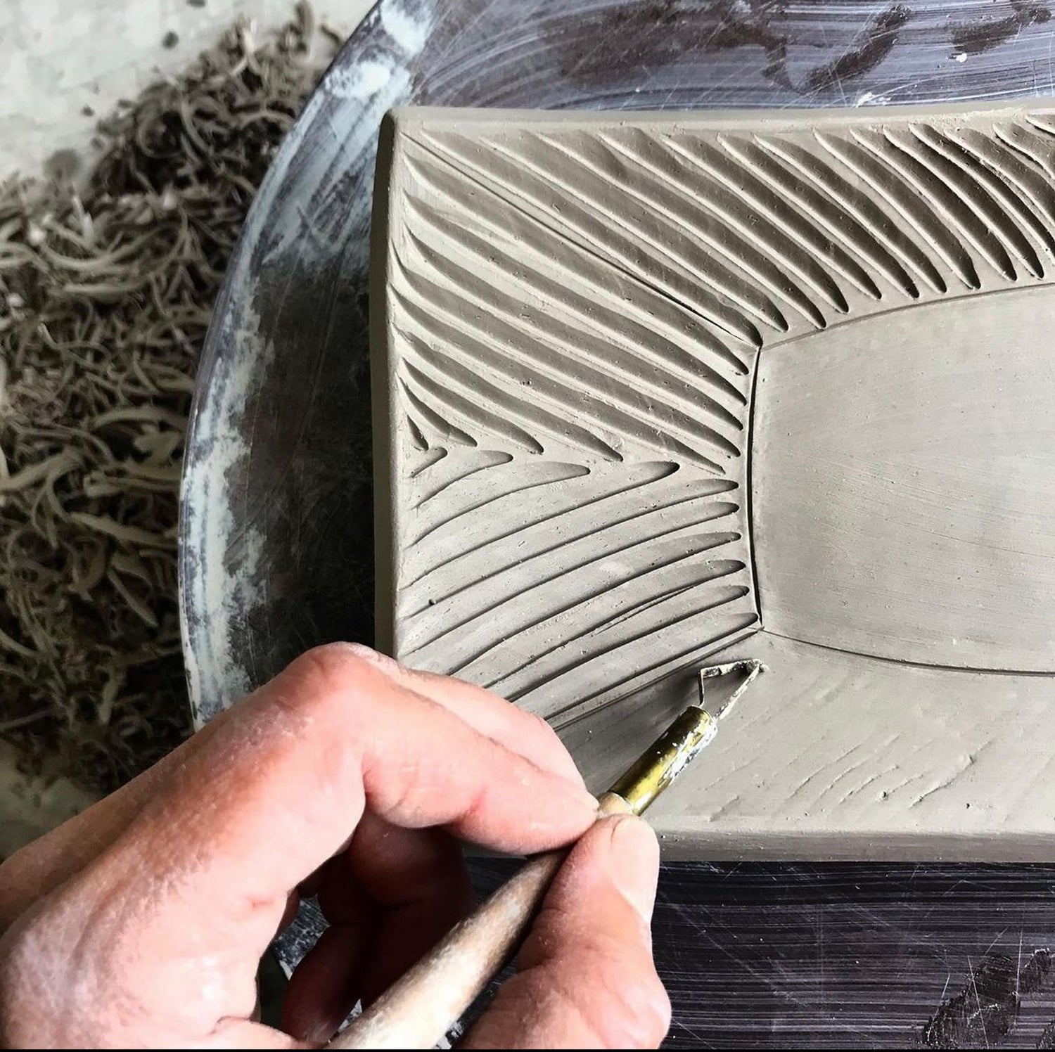 A detail of a hand carving in the clay of an in process plate