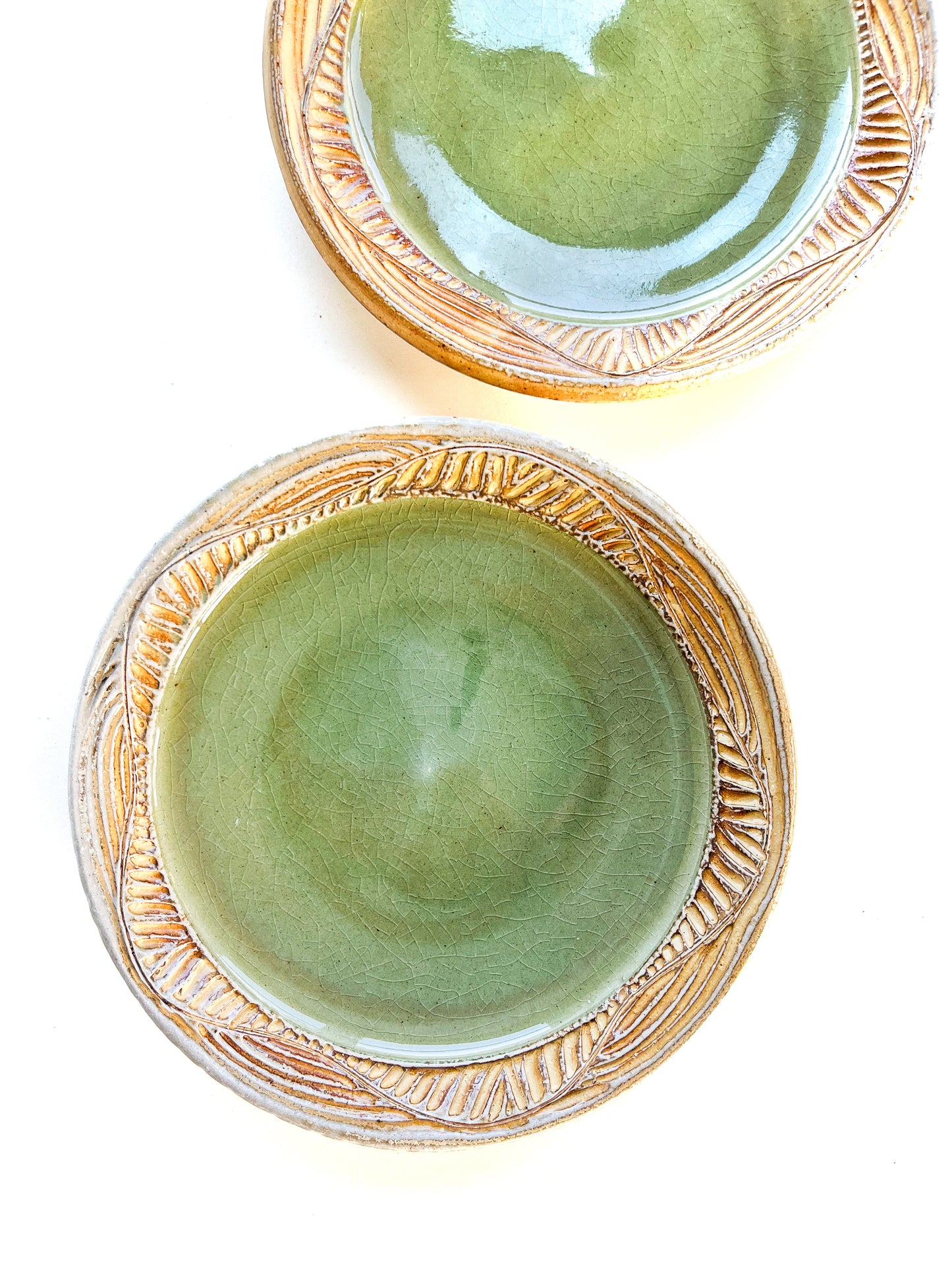 A handmade plate makes your food taste better. This plate is wheel thrown from stoneware clay. The leaf pattern that is hand carved is inspired by nature. The rim is yellow and the interior of the plate is light green.