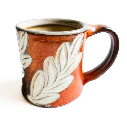 earth toned handmade pottery mug with green leaves