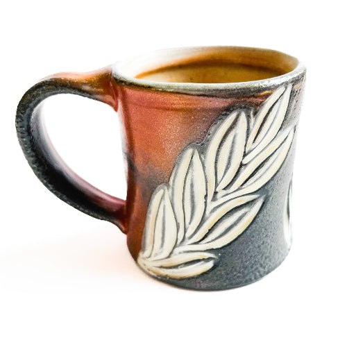 earth toned handmade pottery mug with green leaves