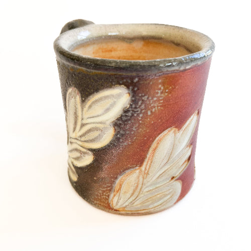 Ceramic cup with leaf design on a white background