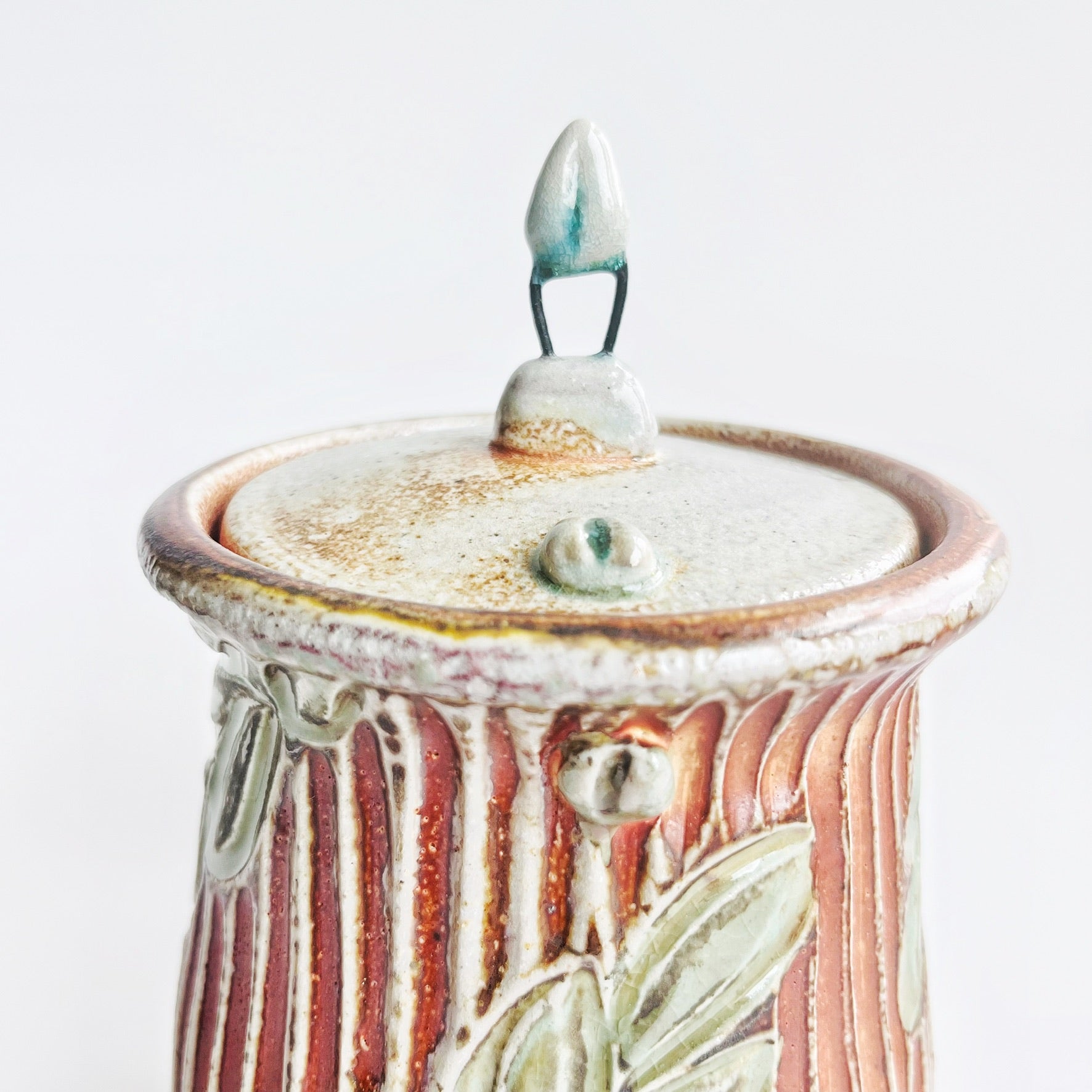 Ceramic jar with decorative lid on a white background