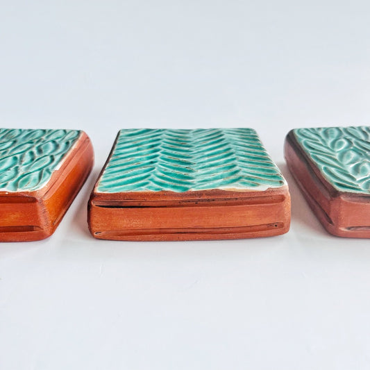 This square wall tile is made from red earthenware clay. The hand carved green leaf pattern contrasts nicely with the red clay. Simply display on your wall alone, or in a grouping.