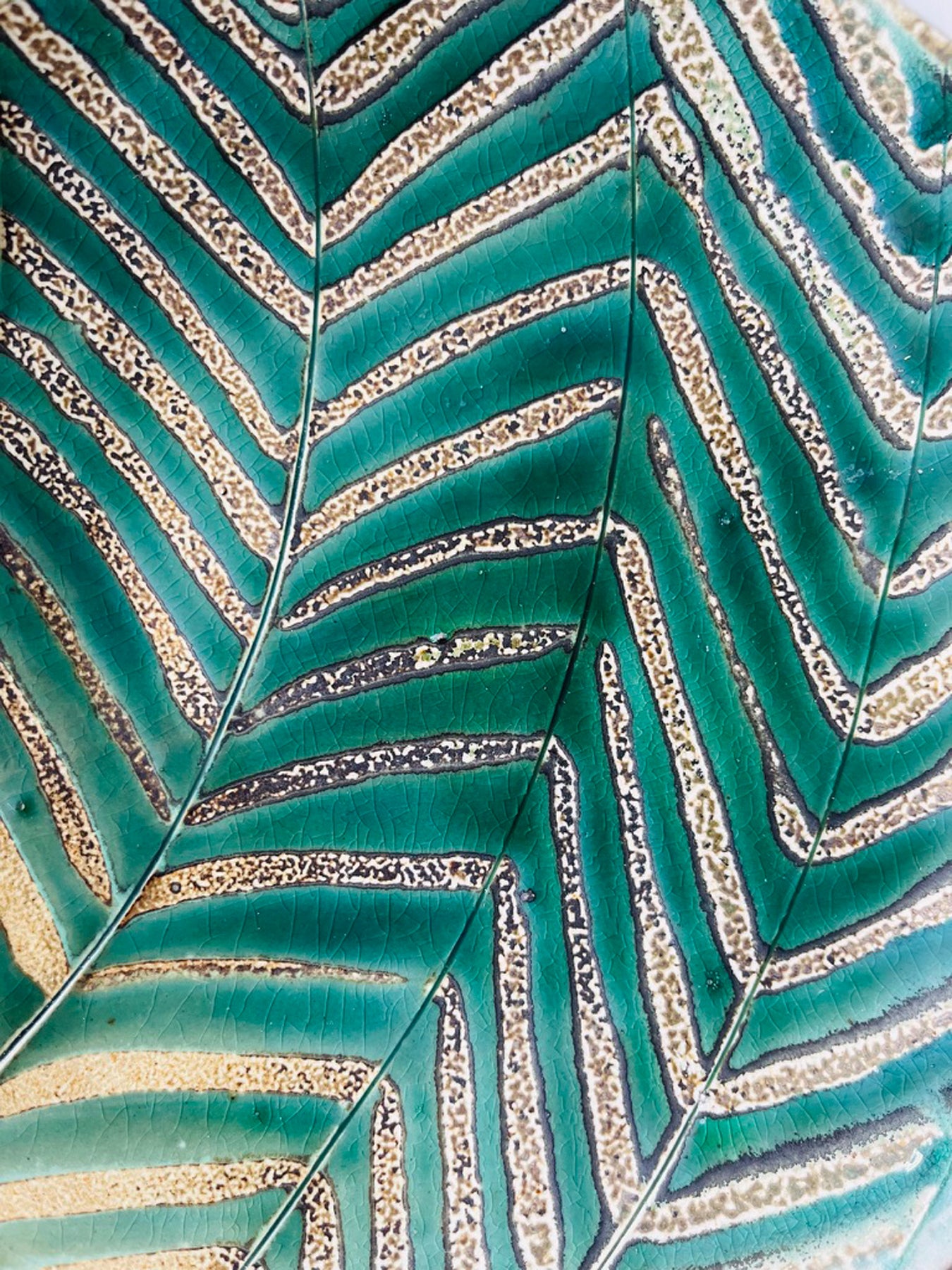A detail of one of Joy Tanner's glazing patterns featuring turquoise chevron lines 