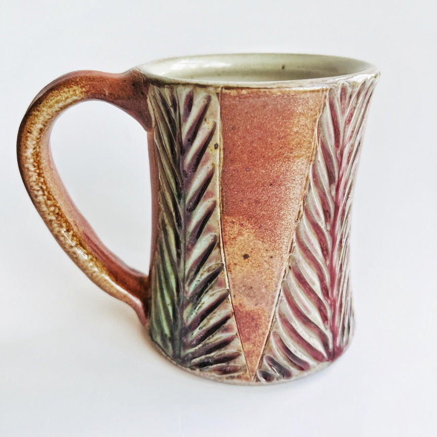 Handmade and carved pottery mug in earth tones