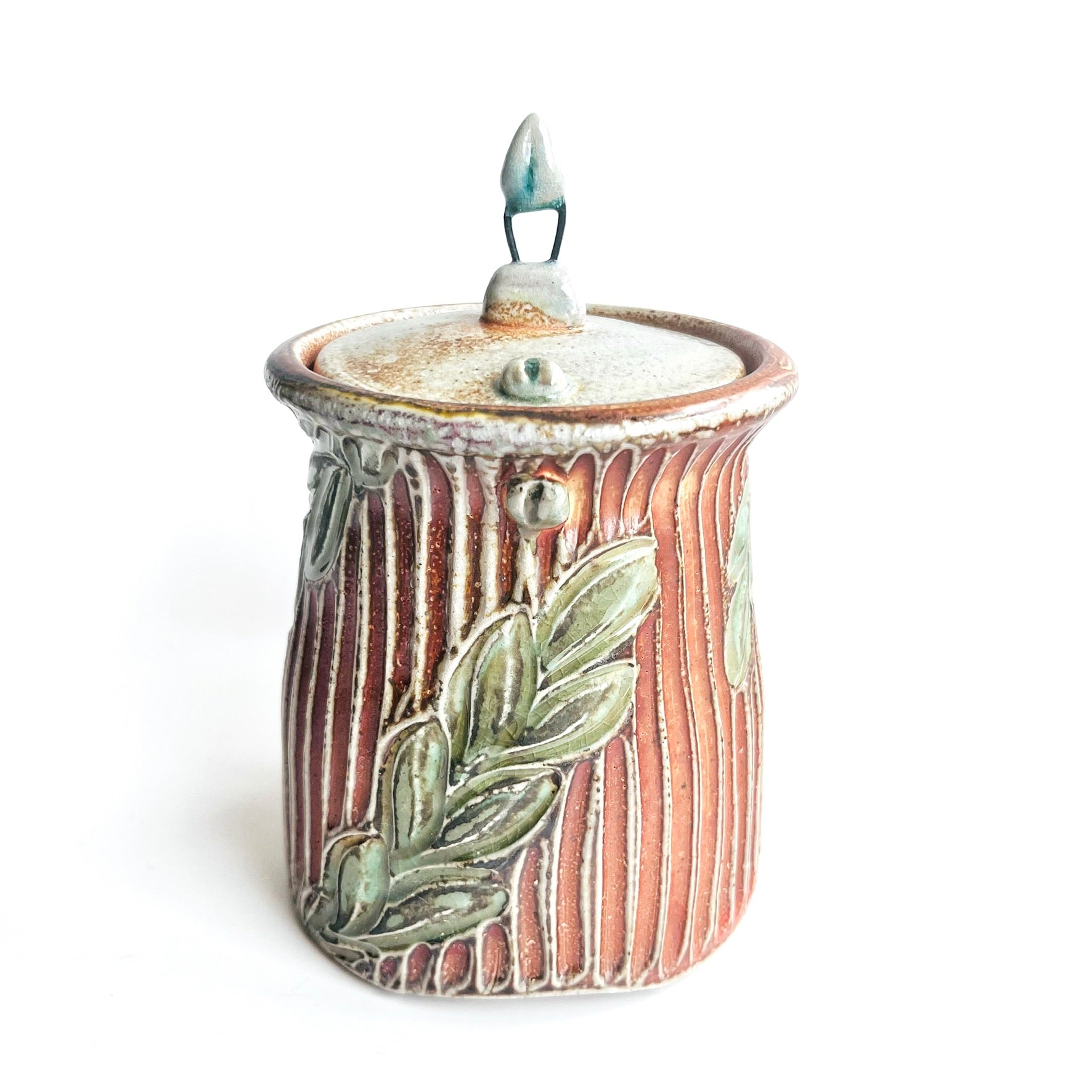 Ceramic jar with lid and leaf design on a white background