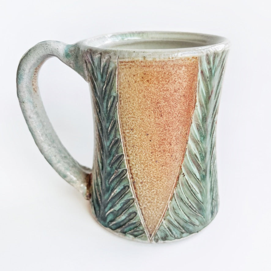 Handmade and carved pottery mug in earth tones