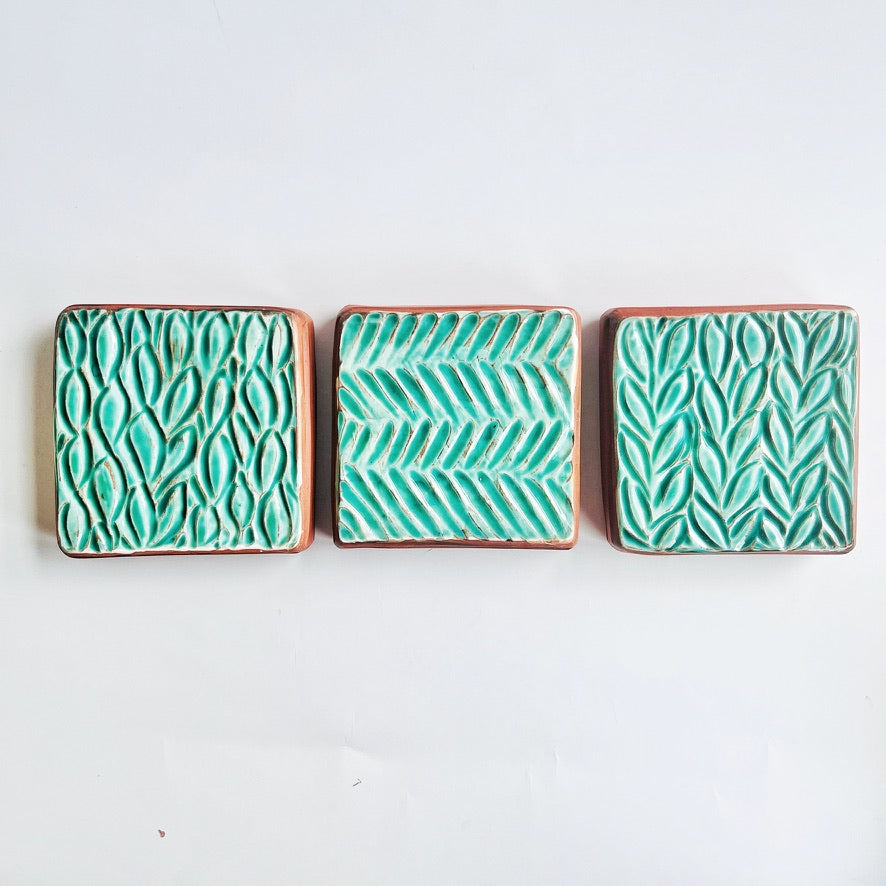 This square wall tile is made from red earthenware clay. The hand carved green leaf pattern contrasts nicely with the red clay. Simply display on your wall alone, or in a grouping.