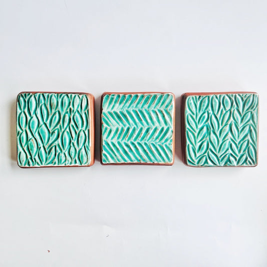This square wall tile is made from red earthenware clay. The hand carved green leaf pattern contrasts nicely with the red clay. Simply display on your wall alone, or in a grouping.