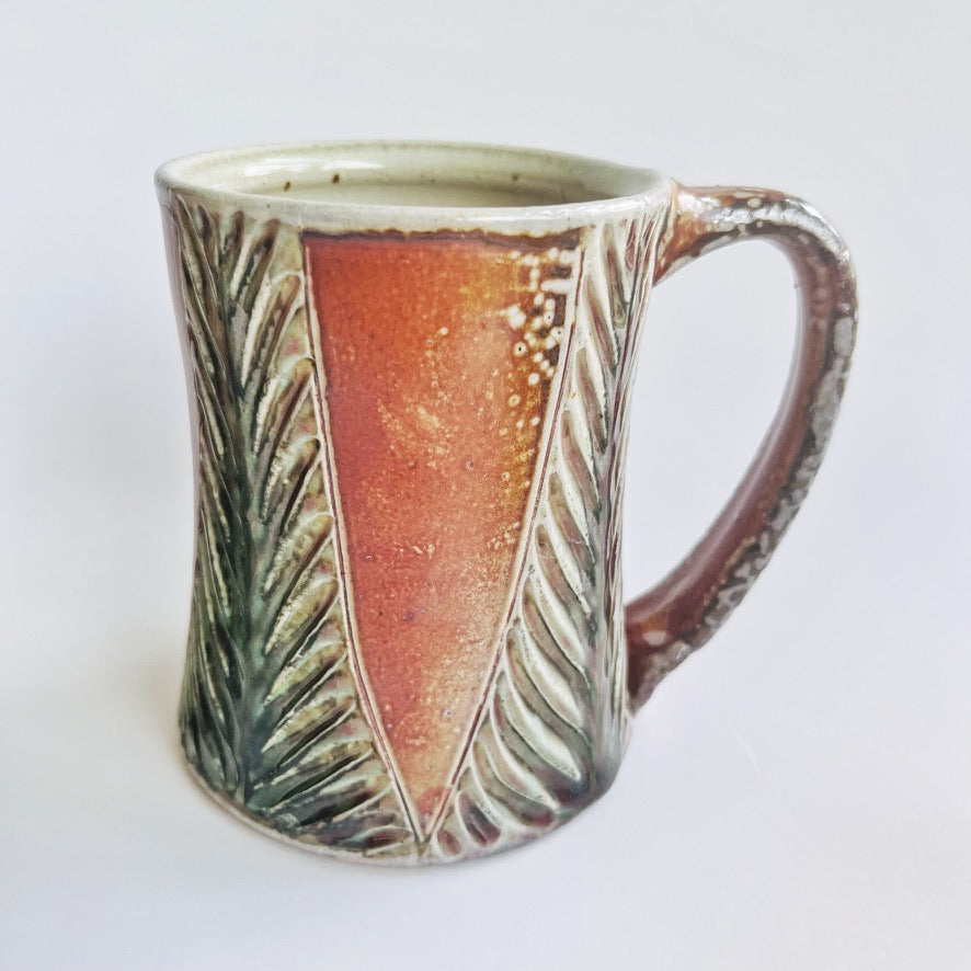 Handmade and carved pottery mug in earth tones