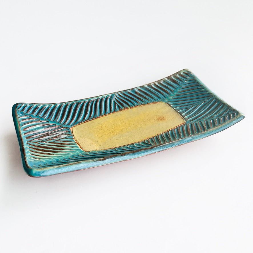 This slab built rectangle dish is great for serving snacks, appetizers, sushi plate, or fun lunch plate! Made from lowfire red earthenware clay, the hand carved turquoise and yellow glaze makes a beautiful statement contrasting with the red clay.