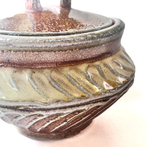 Close-up of a ceramic pot with brown and beige glaze on a white background