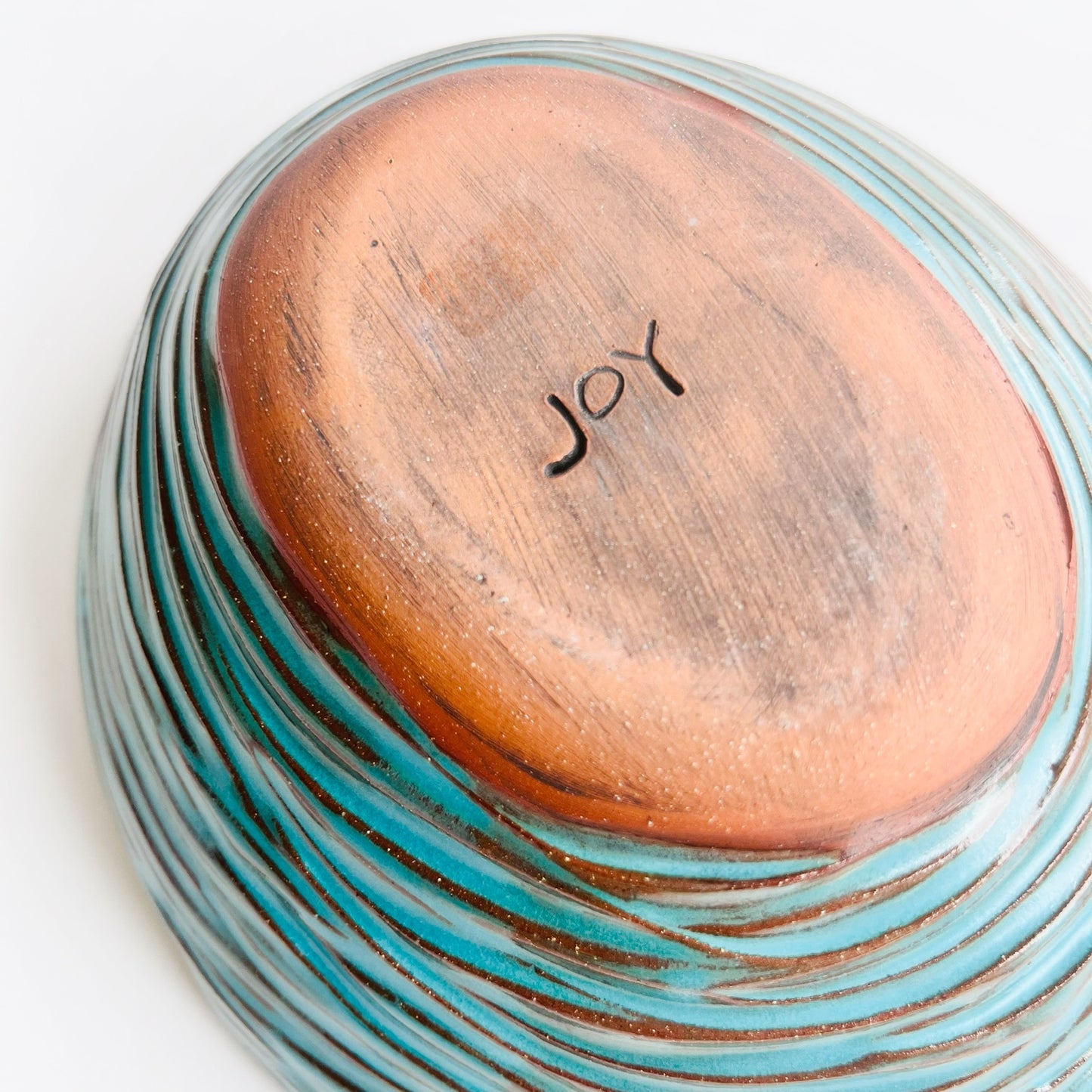 detail of the bottom of a turquoise oval  bowl stamped by the maker, named Joy