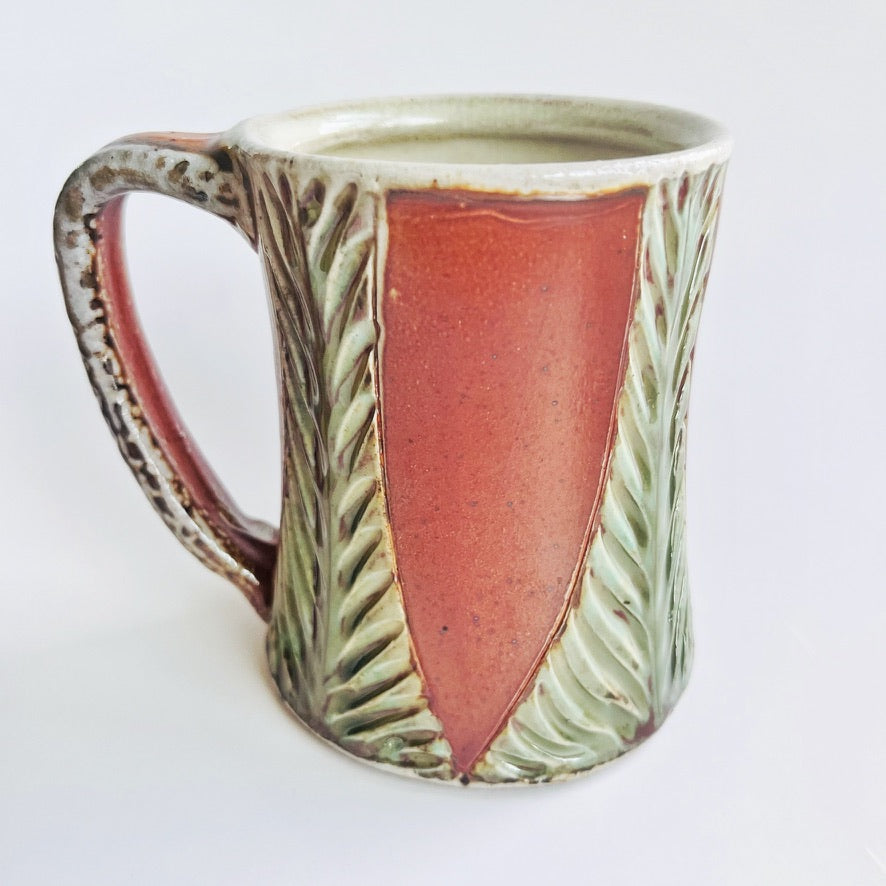 Handmade and carved pottery mug in earth tones