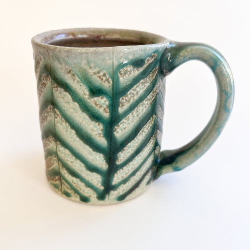 Ceramic mug with green and beige pattern on a white background