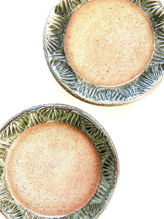 A handmade plate makes your food taste better. This plate is wheel thrown from stoneware clay. The leaf pattern that is hand carved is inspired by nature. The rim of the plate is green and the rest of the plate is varied earth tones.