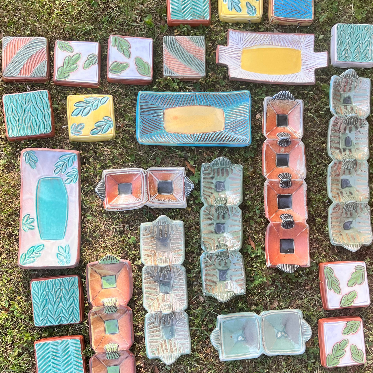 Collection of ceramic tiles with various patterns arranged on grass
