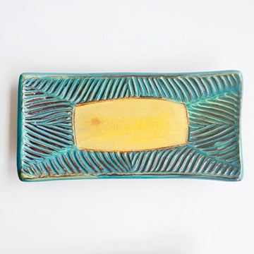 This slab built rectangle dish is great for serving snacks, appetizers, sushi plate, or fun lunch plate! Made from lowfire red earthenware clay, the hand carved turquoise and yellow glaze makes a beautiful statement contrasting with the red clay.